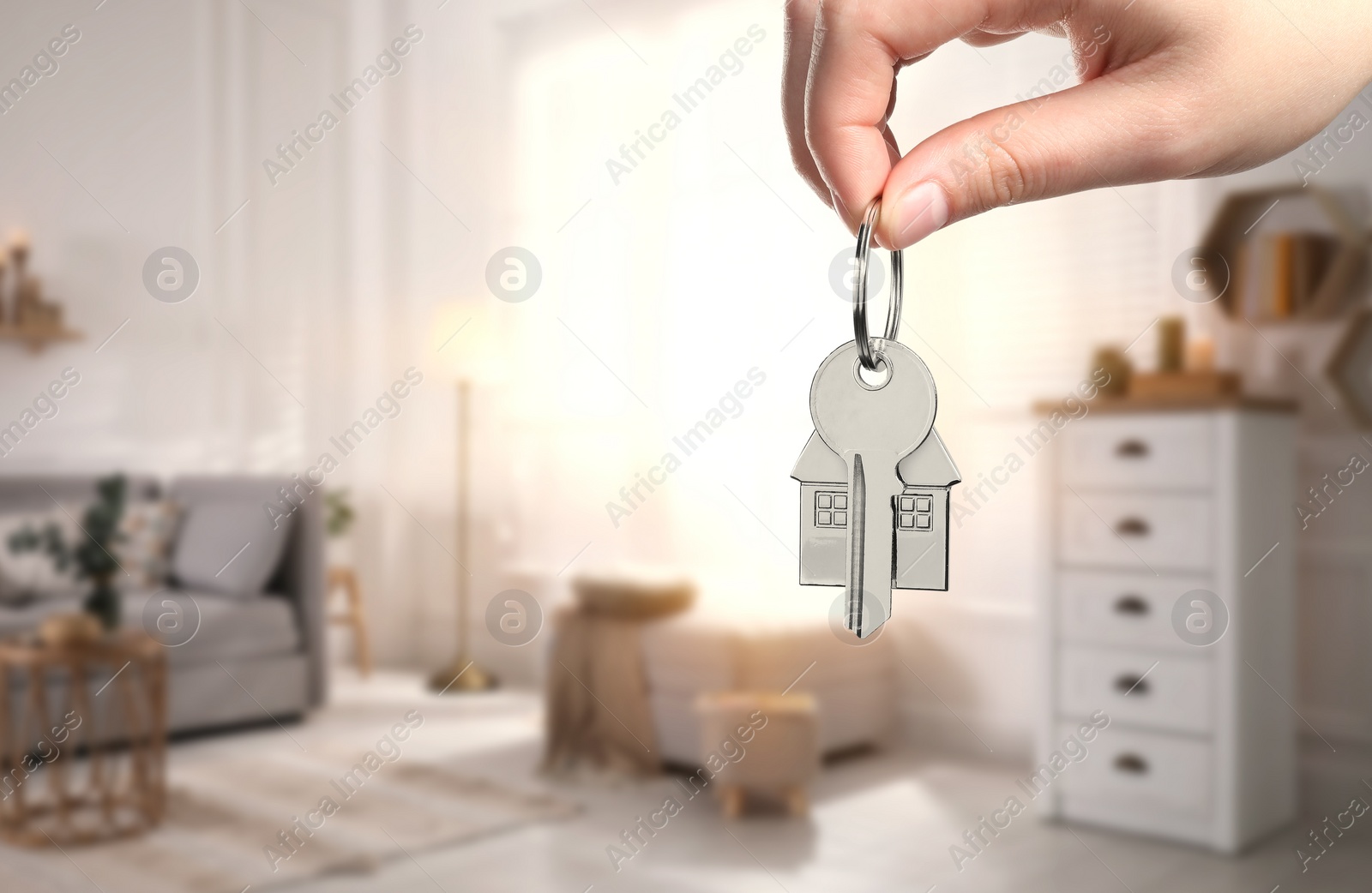 Image of Woman holding house key in room, closeup