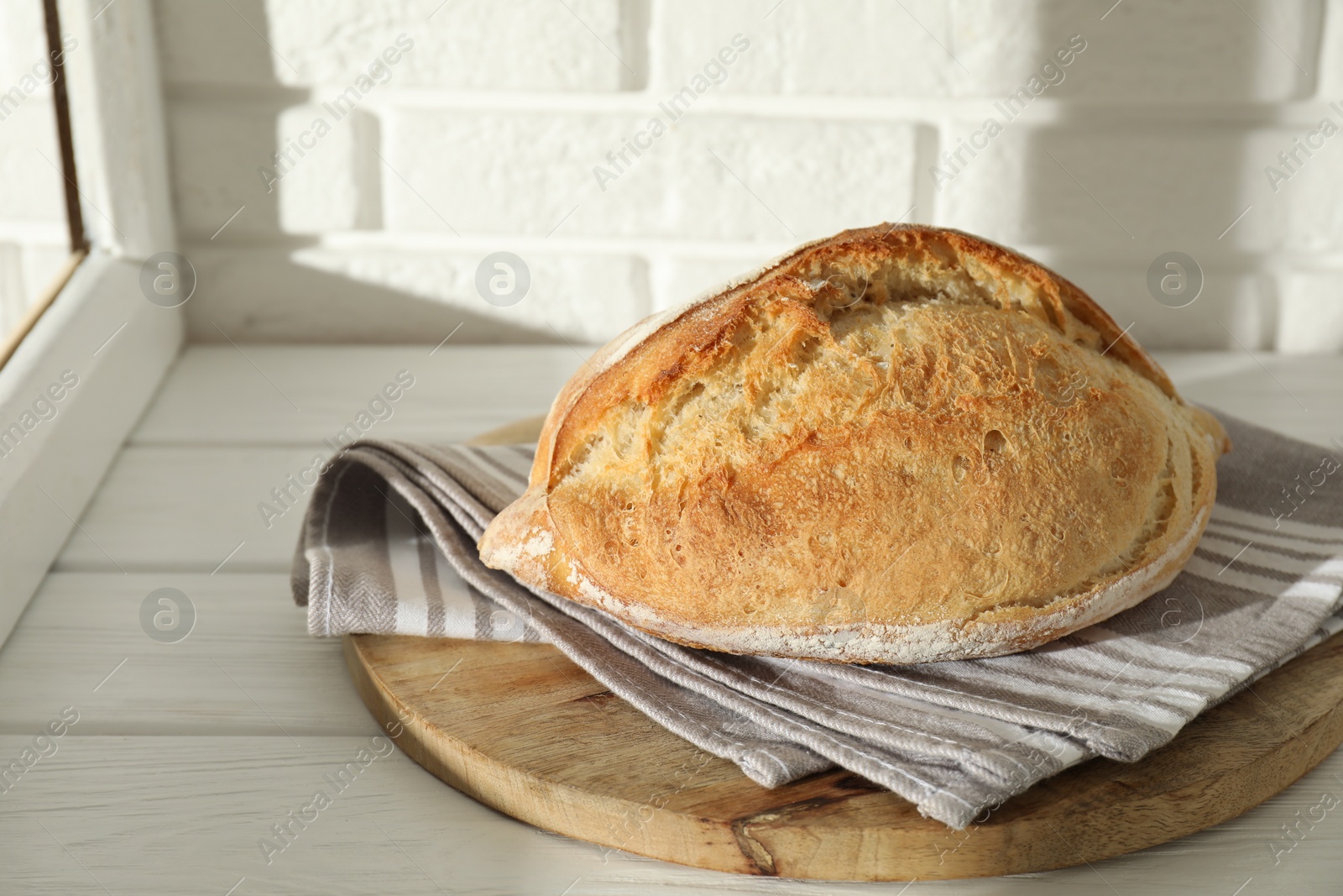 Photo of Freshly baked sourdough bread on white wooden table indoors. Space for text