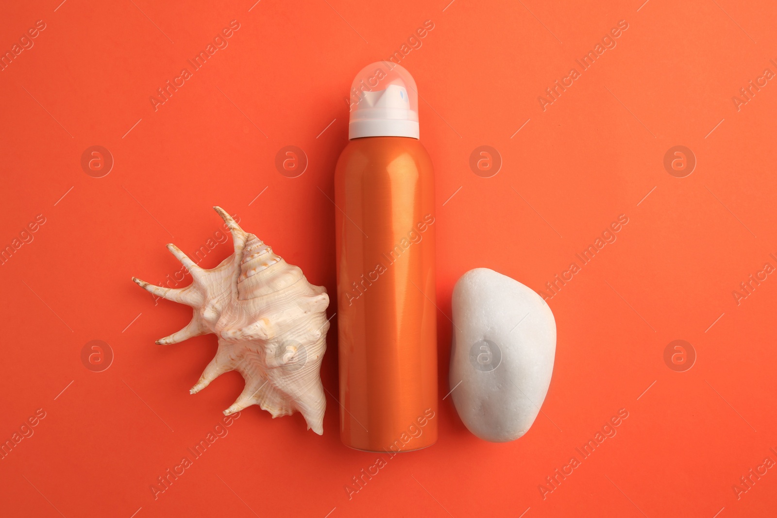 Photo of Bottle of sunscreen, stone and seashell on coral background, flat lay