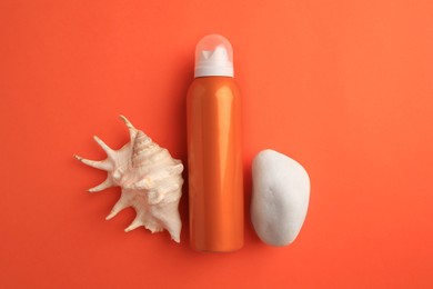 Photo of Bottle of sunscreen, stone and seashell on coral background, flat lay