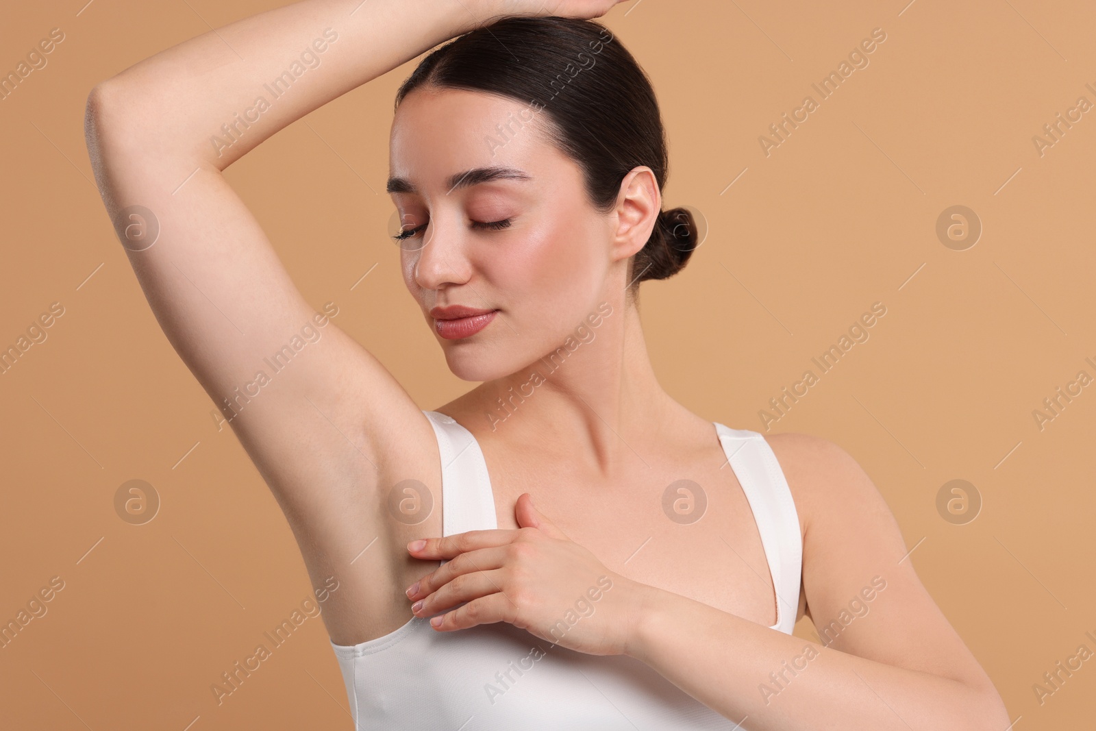 Photo of Beautiful woman showing armpit with smooth clean skin on beige background