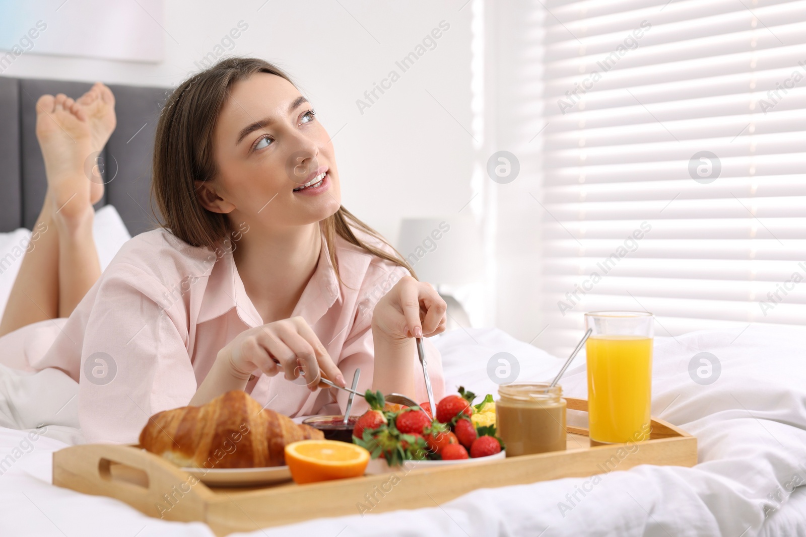 Photo of Smiling woman having tasty breakfast on bed. Space for text