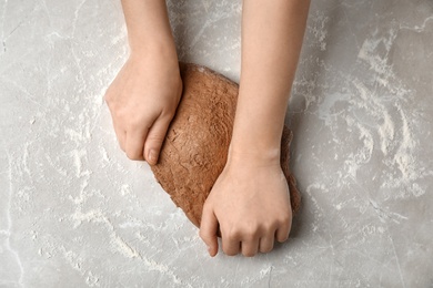 Photo of Woman kneading fresh dough on table, top view