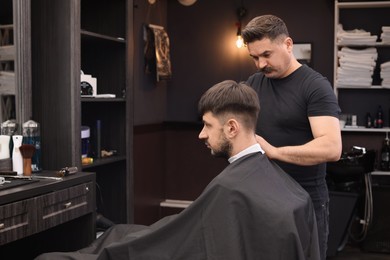 Photo of Professional hairdresser making stylish haircut in barbershop, space for text