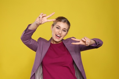 Photo of Happy young businesswoman showing victory gesture on color background