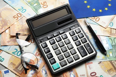 Photo of Calculator, glasses and pen on banknotes, closeup. Eurobonds concept