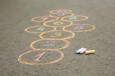 Photo of Hopscotch drawn with colorful chalk on asphalt outdoors, closeup