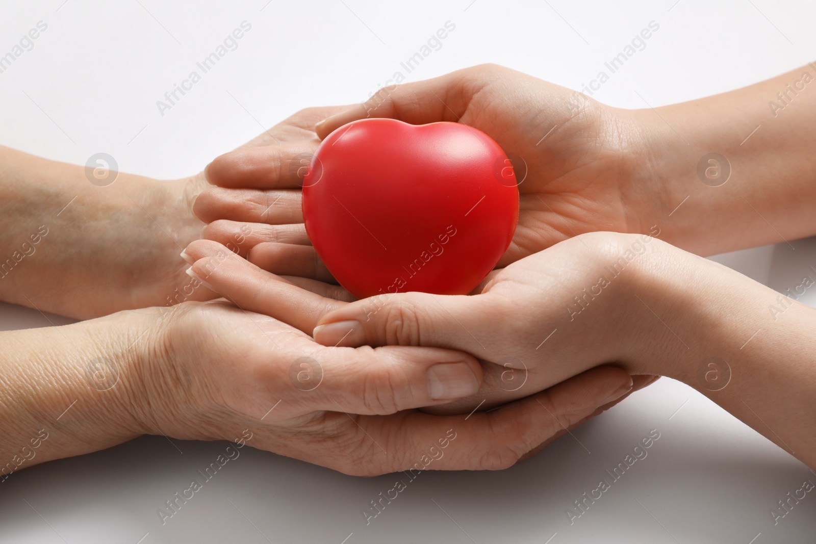 Photo of Young and elderly women holding red heart on white background, closeup