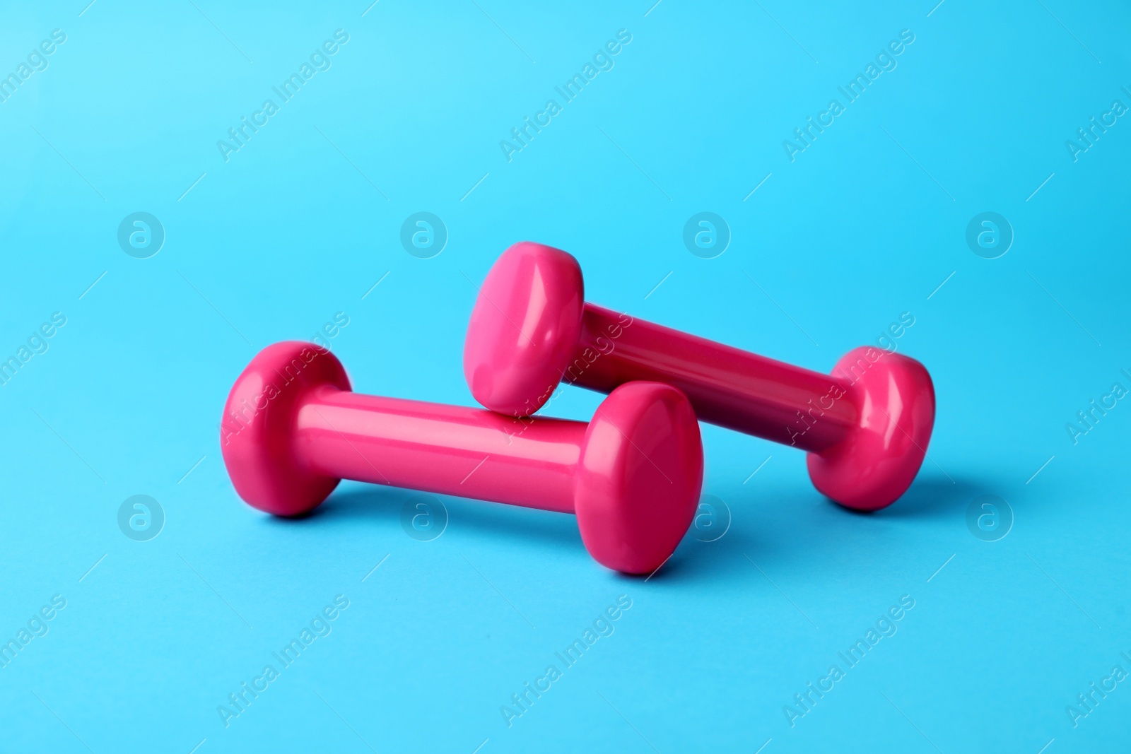 Photo of Two stylish dumbbells on light blue background