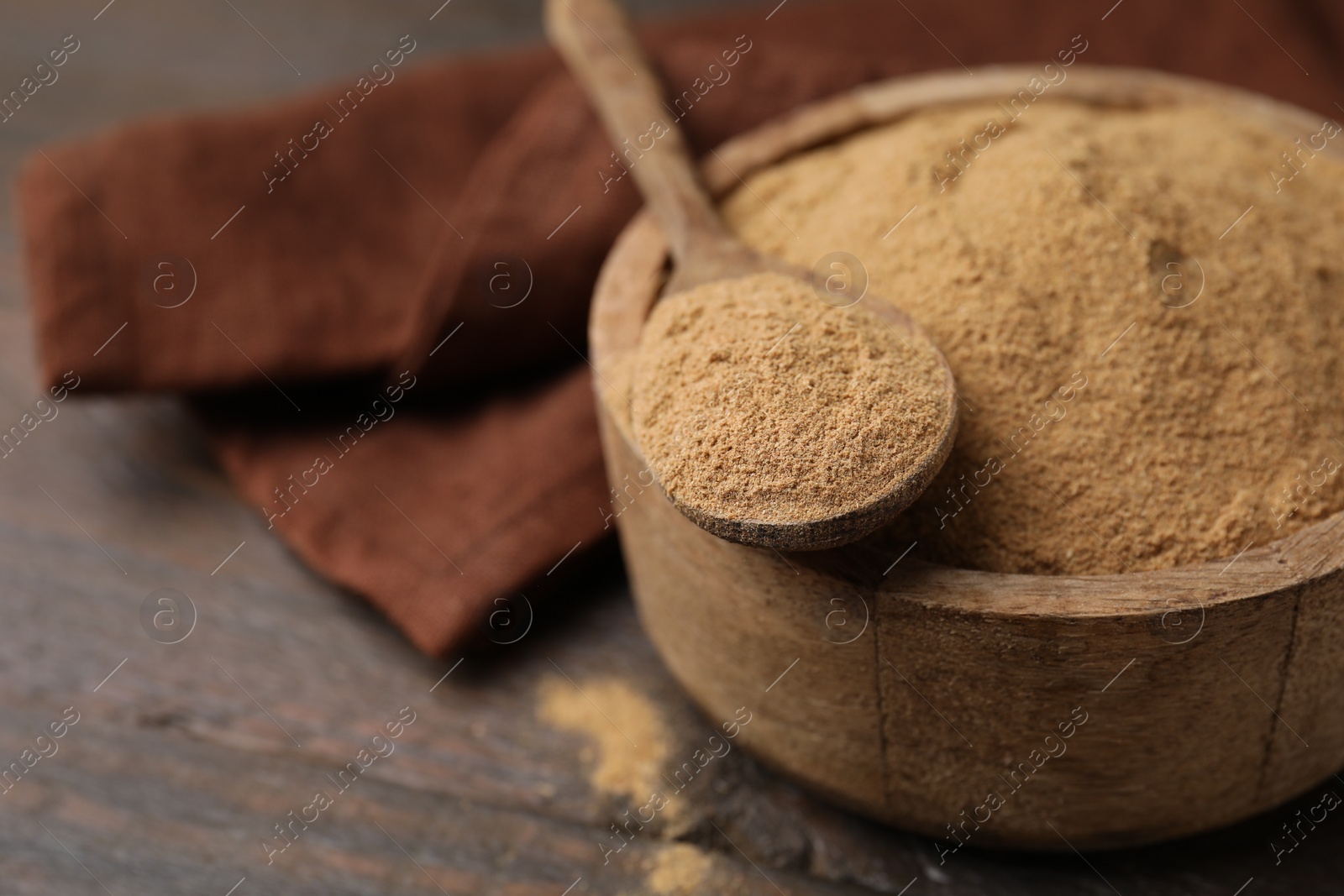 Photo of Dietary fiber. Psyllium husk powder in bowl and spoon on wooden table, closeup. Space for text
