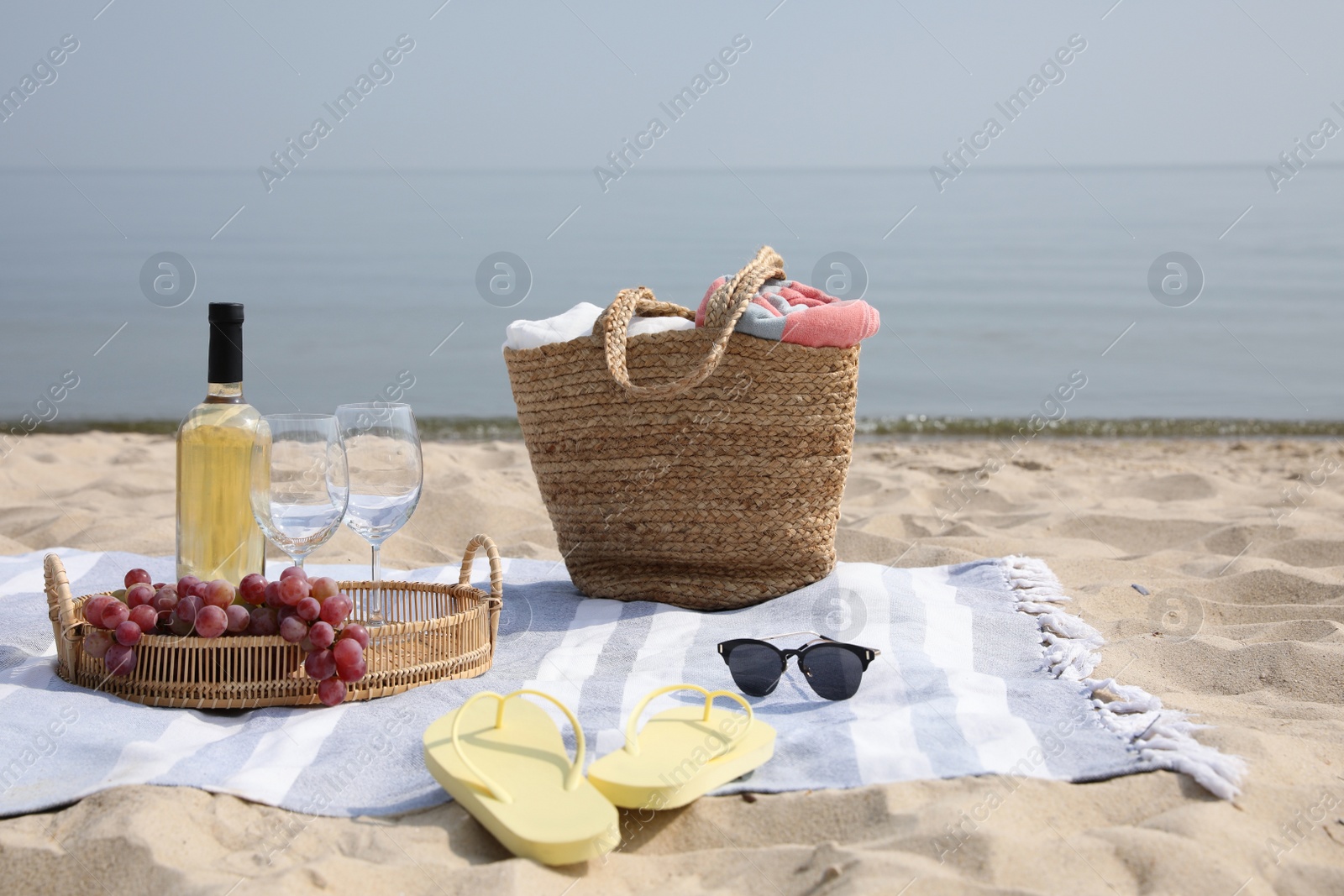 Photo of Bag, blanket, wine and other stuff for beach picnic on sandy seashore