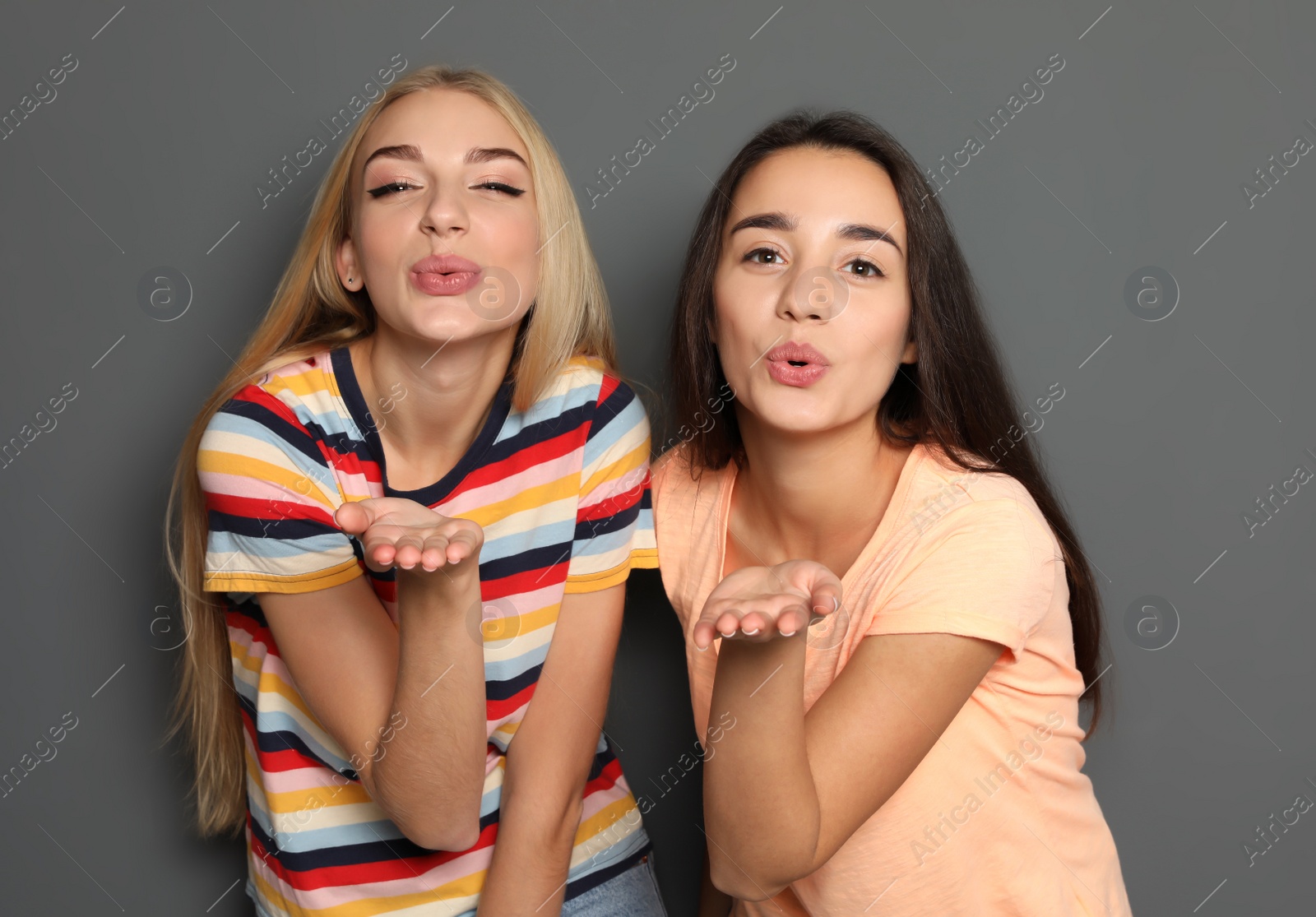 Photo of Beautiful women sending air kisses against gray background