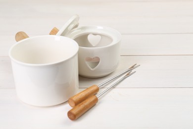 Photo of Fondue set on white wooden table, closeup. Space for text