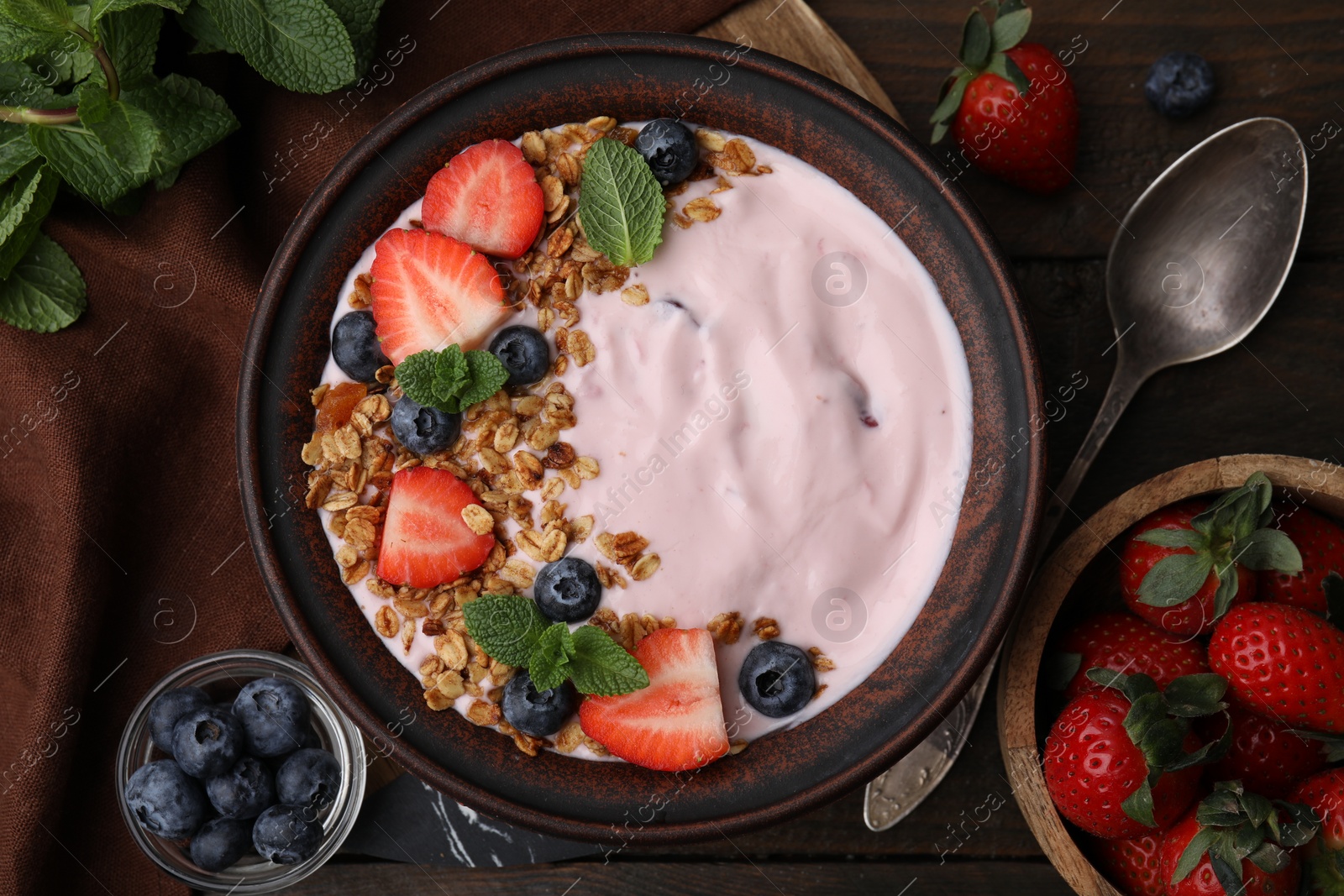 Photo of Bowl with yogurt, berries and granola on wooden table, flat lay