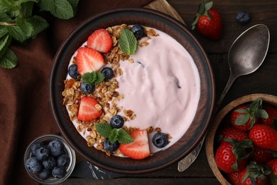 Bowl with yogurt, berries and granola on wooden table, flat lay