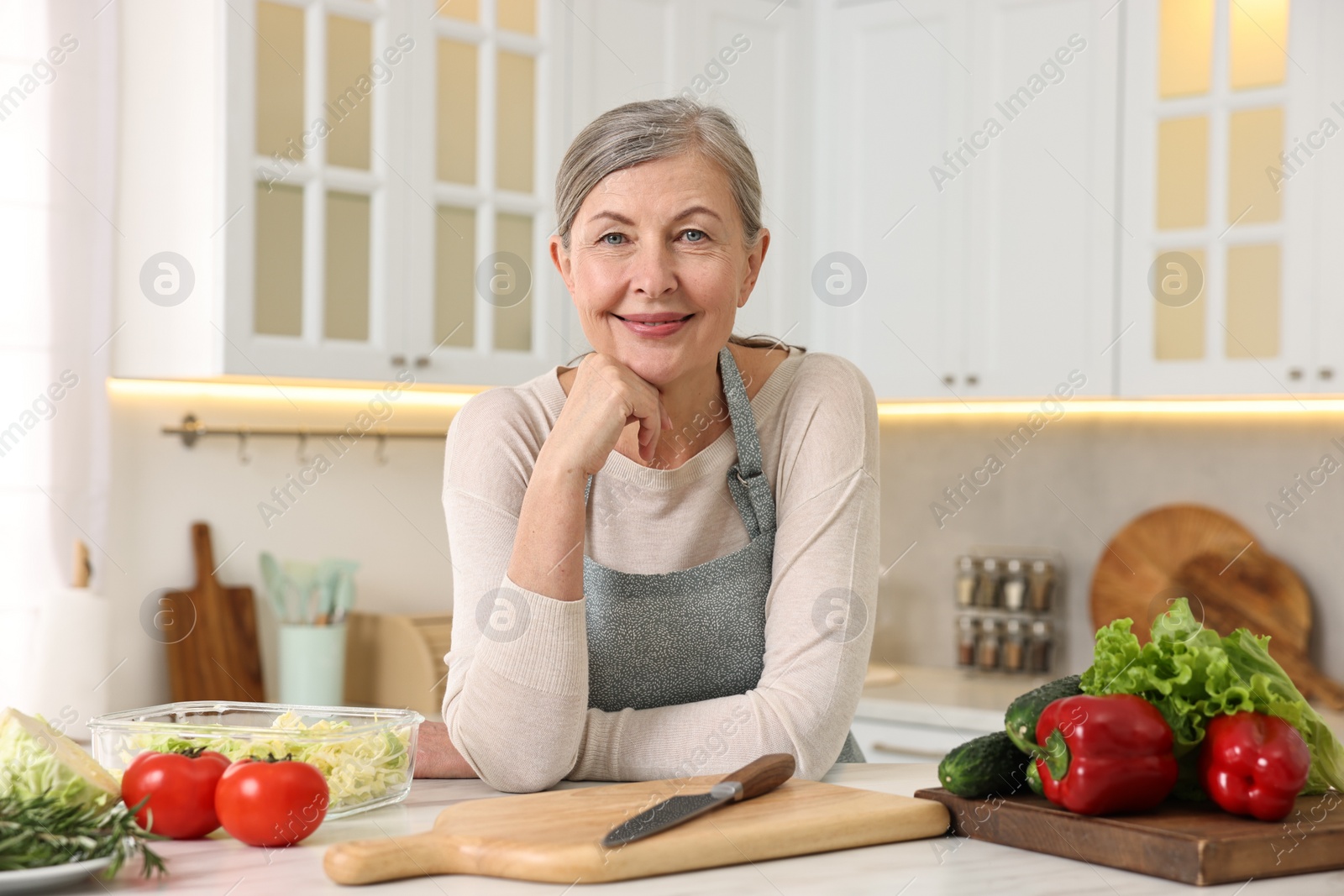 Photo of Happy housewife at white table in kitchen. Cooking process