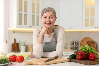 Happy housewife at white table in kitchen. Cooking process