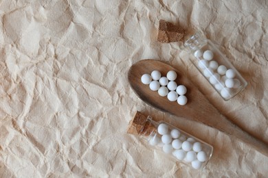Photo of Homeopathic remedy in bottles and spoon on wrinkled paper, flat lay. Space for text