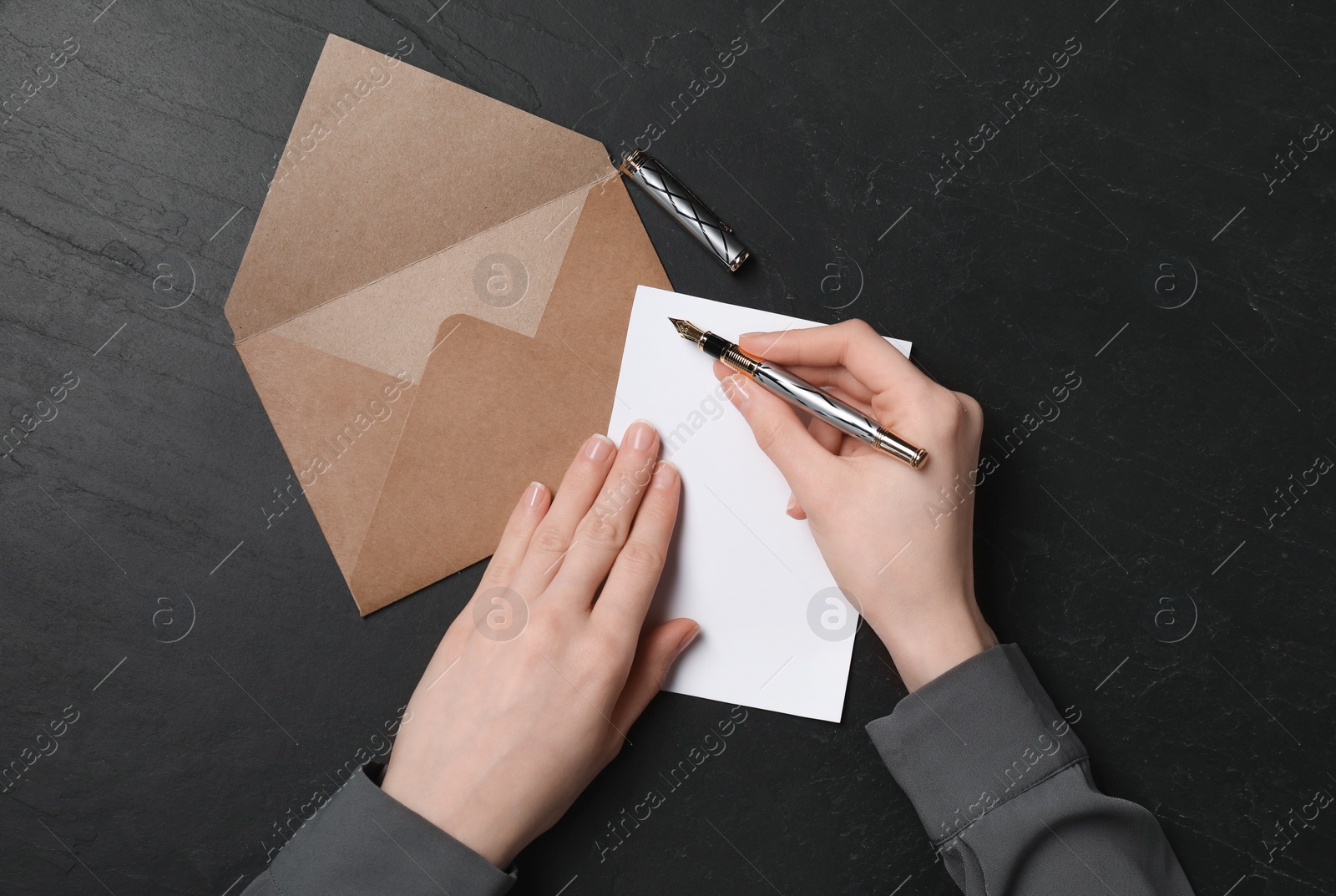 Photo of Woman writing letter at black textured table, top view