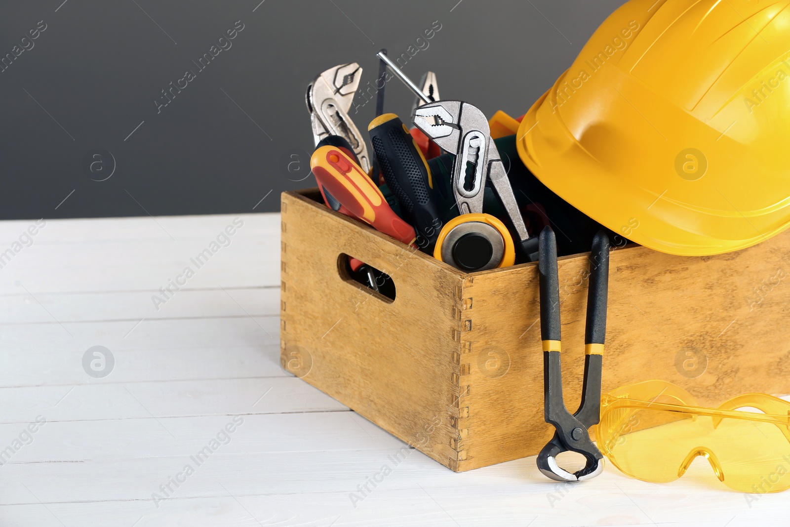 Photo of Wooden box with different tools for repair on white table, space for text