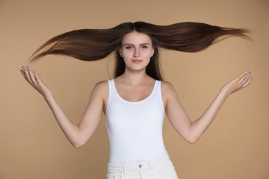 Photo of Young woman with strong healthy hair on beige background