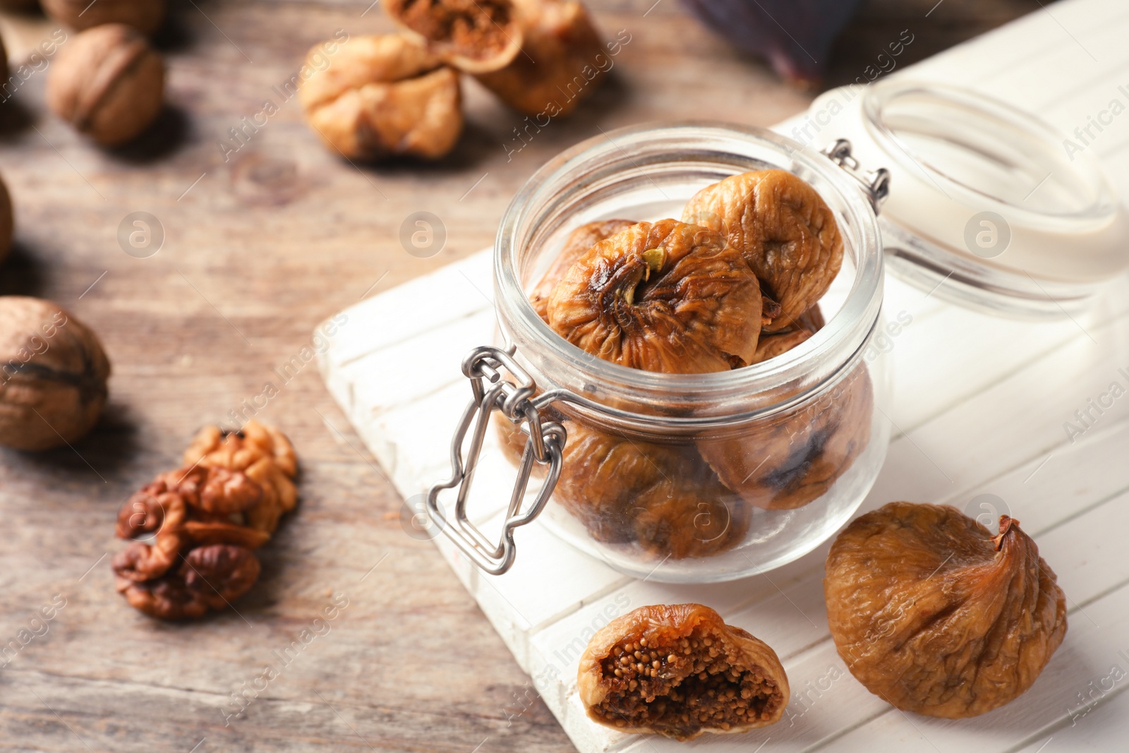 Photo of Jar with delicious dried figs on wooden board. Organic snack
