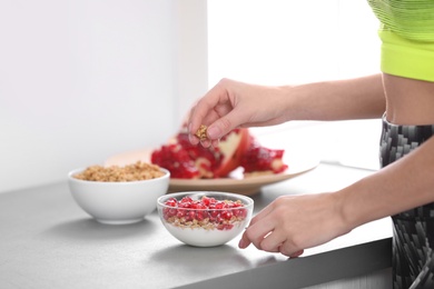 Photo of Young woman in fitness clothes preparing healthy breakfast at home, closeup