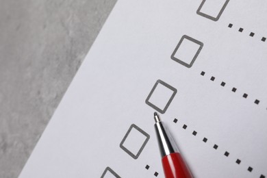 Photo of Paper sheet with checkboxes and pen on light grey table, closeup. Checklist