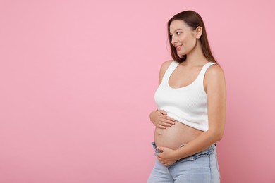 Photo of Beautiful pregnant woman with long hair on pink background, space for text