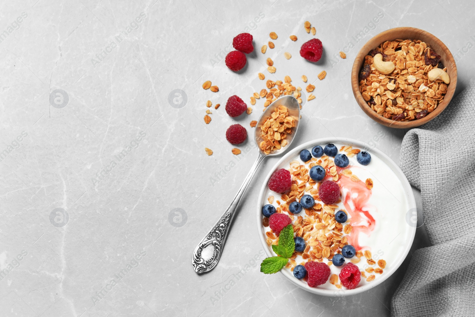 Photo of Healthy homemade granola with yogurt and berries served on light grey table, flat lay. Space for text