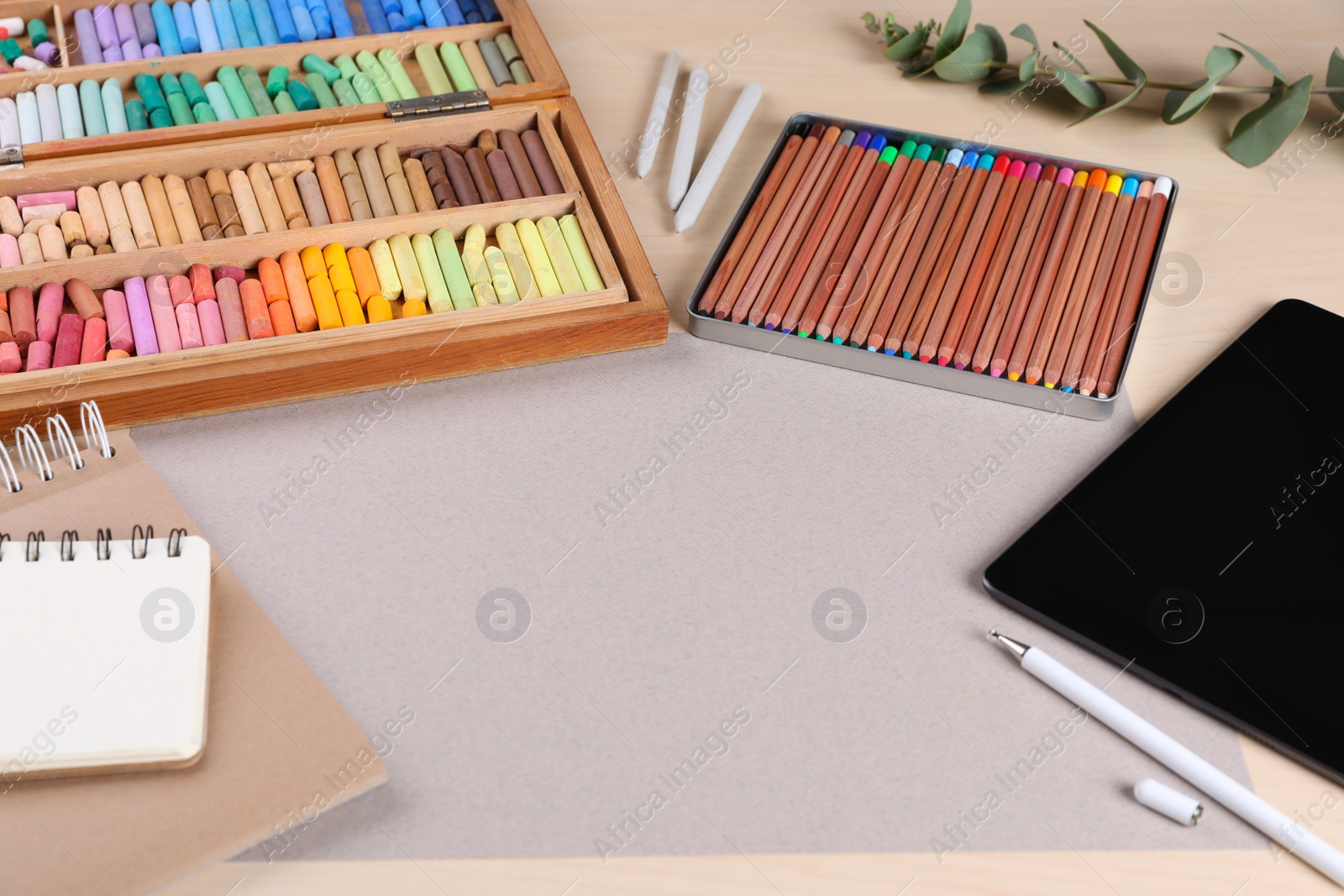 Photo of Blank paper, soft pastels and other drawing supplies on wooden table at artist's workplace. Space for design