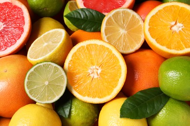 Photo of Different fresh citrus fruits and leaves as background, above view