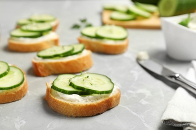 Photo of Traditional English cucumber sandwiches on grey table. Space for text