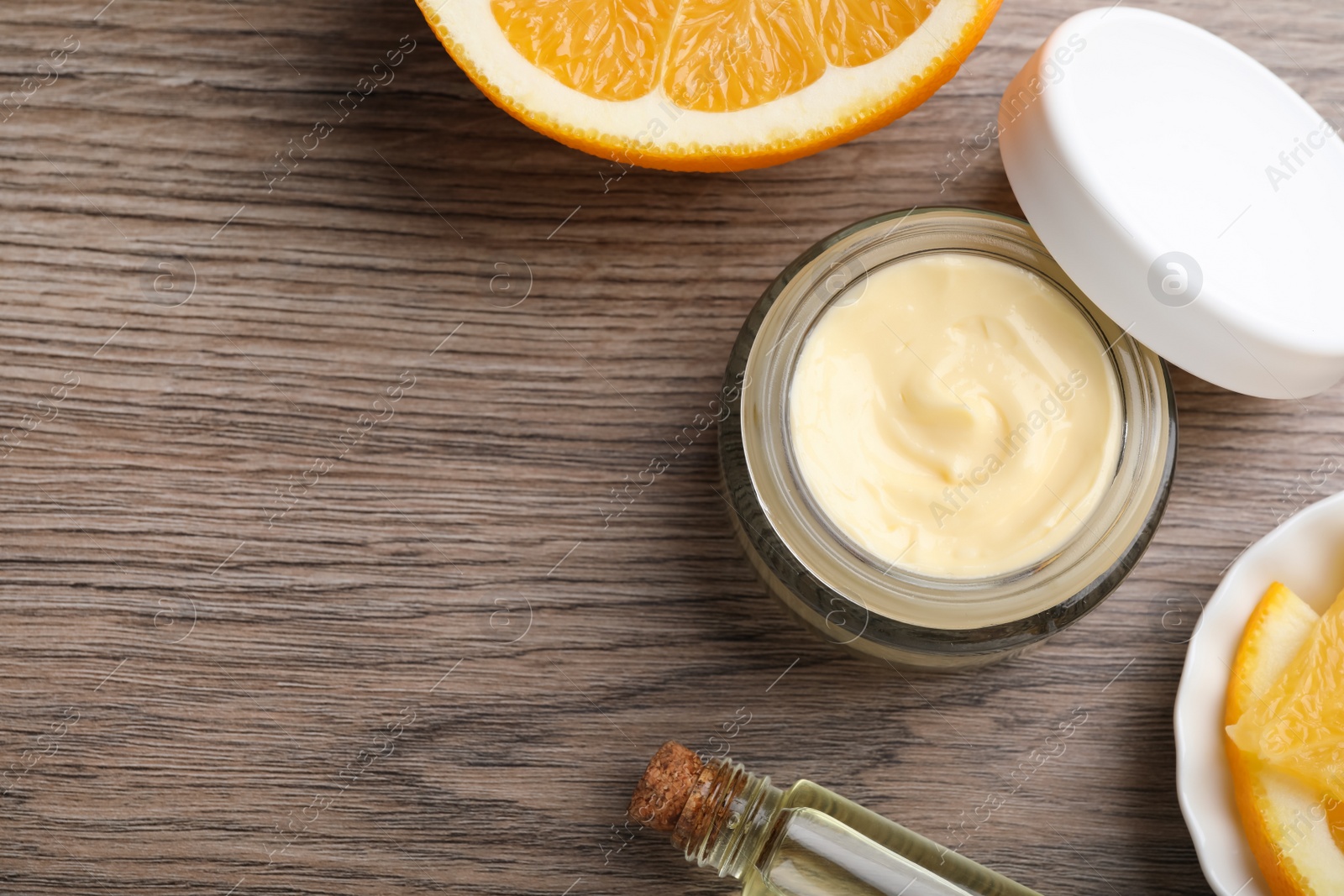 Photo of Body cream and cosmetic product with orange on wooden table, flat lay. Space for text
