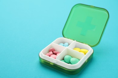 Plastic box with different pills on light blue background