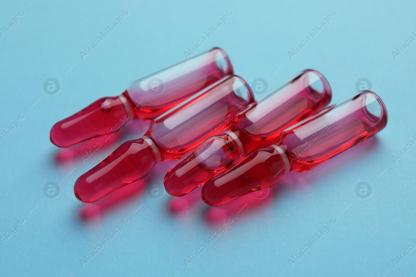 Photo of Many medical ampoules with solution on light blue background