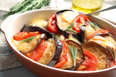 Photo of Baked eggplant with tomatoes, cheese and rosemary in dishware, closeup