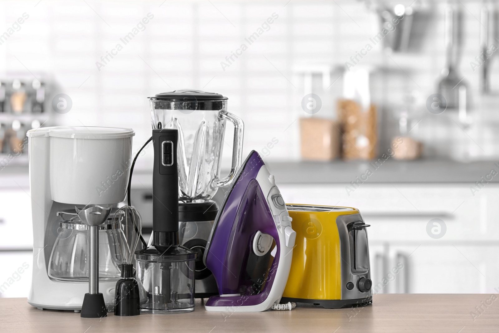 Photo of Household and kitchen appliances on table against blurred background