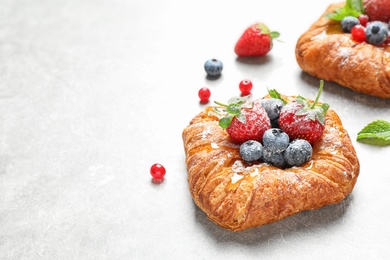 Photo of Fresh delicious puff pastry with sweet berries on light background. Space for text