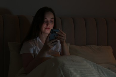 Woman using smartphone in bed at night. Internet addiction