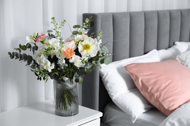 Bouquet of beautiful flowers on nightstand in bedroom