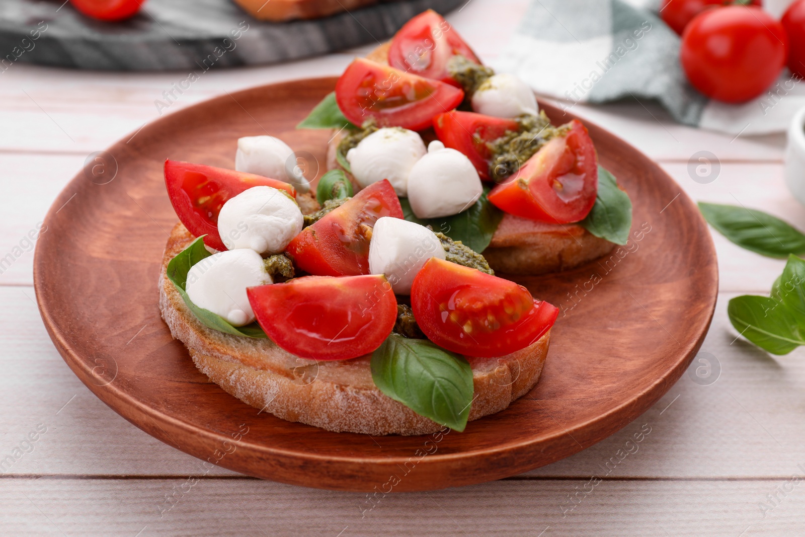 Photo of Delicious Caprese sandwiches with mozzarella, tomatoes, basil and pesto sauce on white wooden table, closeup