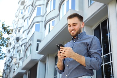 Photo of Young man with smartphone on city street