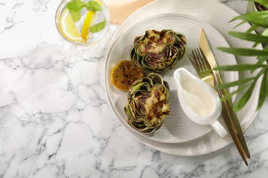 Photo of Tasty grilled artichokes served on white marble table, flat lay. Space for text