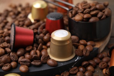 Photo of Coffee capsules and beans on wooden table, closeup