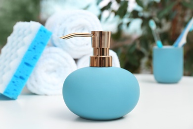 Photo of Soap dispenser and bathroom essentials on table against blurred background