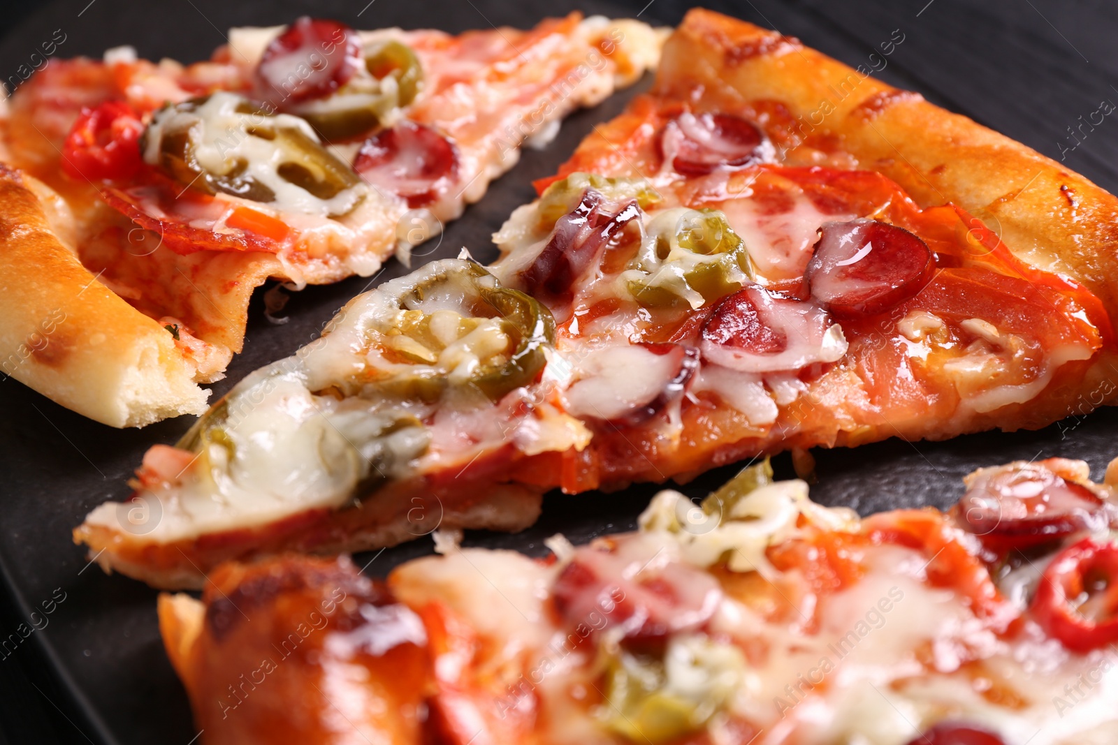 Photo of Pieces of delicious pizza Diablo on textured board, closeup