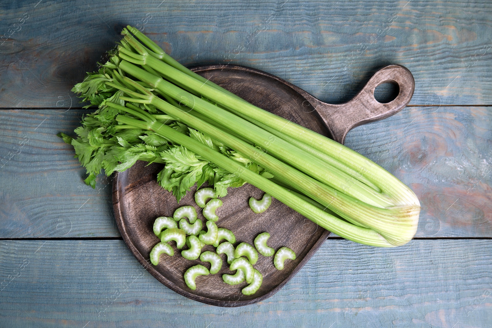 Photo of Fresh ripe celery on blue wooden table, top view