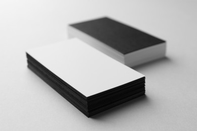 Photo of Blank black and white business cards on light background, closeup. Mockup for design