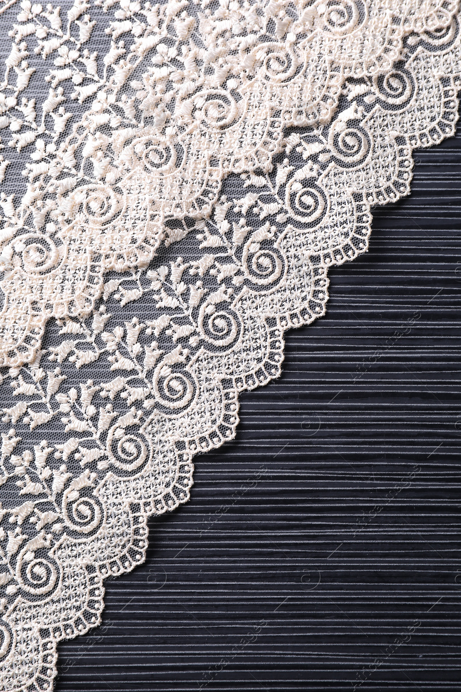 Photo of White lace on black table, top view. Space for text